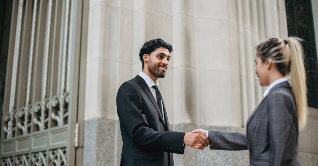 pexels photo 4963440 4963440 Two business professionals in formal attire shaking hands outside an elegant building, signifying partnership.